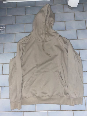 En beige Hoodie från H&M - Jag säljer en beige Hoodie från H&M med storleken M och den har två snören och en ficka och en luva tröjan passar bra till en massa stilar med jeans och mjukisbyxor