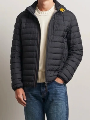 Svart pufferjacka med dragkedja - Säljer en svart pufferjacka med horisontella quiltade sektioner och hel dragkedja framtill. Jackan har en hög krage och en liten gul detalj vid axeln. Perfekt för kyliga dagar och enkel att matcha med jeans eller hoodie.