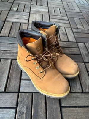 Timberland boots  - Säljer ett par Timberland boots i beige med bruna detaljer och orange foder. Skorna är i storlek 38 och har använts ett fåtal gånger. Kan skickas med PostNords spårbara frakt! 