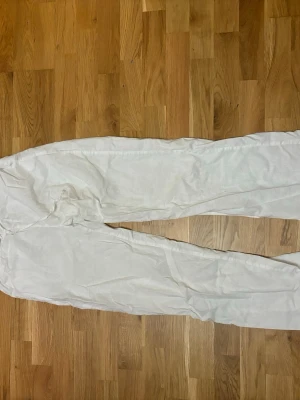 Vita linnebyxor från Gina Tricot - Säljer ett par fräscha vita linnebyxor från Gina Tricot i storlek S. Byxorna har elastisk midja med snörning och är tillverkade i ett lätt och luftigt linnematerial. Perfekta för varma dagar och chill stil. Är uppsprättade längst ner men inget som syns