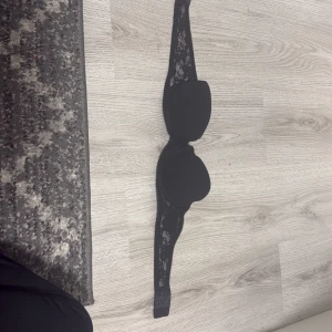 Svart axelbandslös BH från H&M - Säljer en axelbandslös svart BH från H&M i storlek 80A. BH:n har snygga spetsdetaljer längs banden och en stilren, enkel design. Perfekt för dig som gillar en klassisk look med lite extra edge. Spetsen ger en feminin touch och den svarta färgen gör den lätt att matcha.