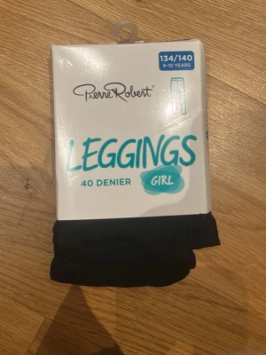 Svarta leggings från Pierre Robert - Svarta leggings från Pierre Robert, 40 denier, tillverkade i Italien. Materialet är mjukt och stretchigt med 93% polyamid och 7% elastan, vilket gör dem riktigt sköna att bära. Perfekta för dig som vill ha ett enkelt och stilrent plagg i garderoben.