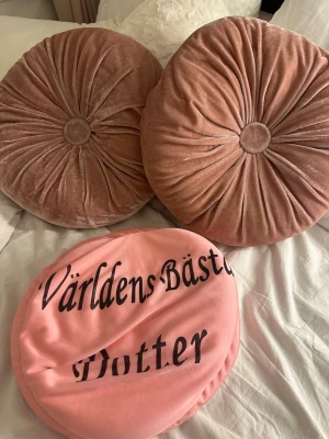 Prydnadskuddar - Bilderna visar endast runda kuddar i rosa och beige sammet samt en kudde med texten 'Världens Bästa Dotter'. 