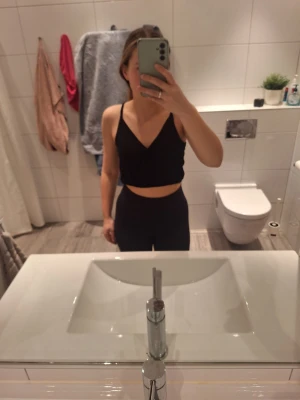 Svart croppad linnetopp Pull&Bear - Svart croppad linnetopp från Pull&Bear med tunna axelband och omlott framtill. Toppen har en luftig passform och elastisk nederkant, perfekt till varma dagar. Enkel och stilren design som är lätt att matcha med olika outfits.