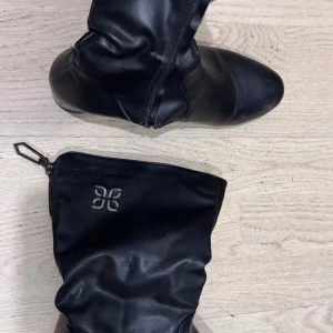 Svarta stövlar dragkedja - Snygga svarta stövlar från Röhnisch i mjukt skinn med rund tå och låg klack. Stövlarna har dragkedja på sidan och en diskret logga på skaftet. Perfekta för dig som vill ha en stilren look med en sportig touch.