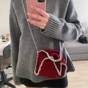 Röd stickad axelväska med kedja - Säljer en snygg röd stickad axelväska med silverfärgad kedja som axelrem och runt kanterna. Perfekt för dig som vill ha något unikt och trendigt. 