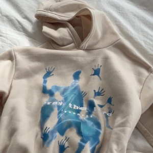 Beige hoodie med blått tryck - Fin beige hoodie som liknar den från Reenness med unikt blått tryck av siluetter och händer på framsidan. Tröjan har huva, ribbade muddar och en avslappnad passform. Jättemjuk och bekväm 💗