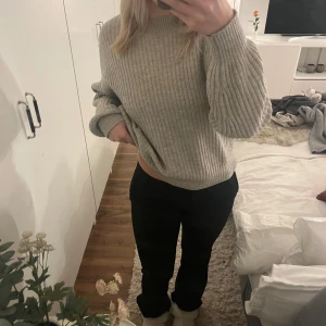 Ribbstickad grå tröja - Mysig ribbstickad tröja i ljusgrått med rund hals och långa ärmar. Tröjan har en loose passform och är perfekt för kyligare dagar. Enkel och stilren design som är lätt att matcha med olika outfits.