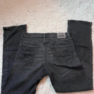 Replay svarta jeans - Säljer ett par svarta Replay jeans med klassisk femficksdesign och snygga detaljer på bakfickorna.Perfekta för dig som gillar en stilren look. Jeansen passar dig som är runt 160-170
