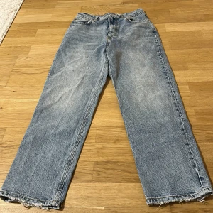 Ljusblå raka jeans från Gina Tricot - Säljer ett par ljusblå jeans från Gina Tricot med rak passform och klassisk femficksdesign. Jeansen har råa, fransiga benslut och normal midja. Perfekta för en avslappnad och trendig look.