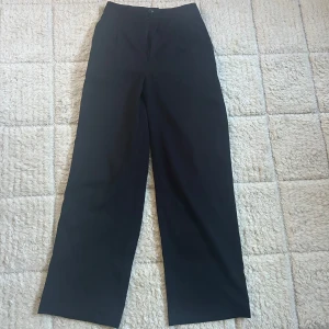 Svarta kostymbyxor - Svarta kostymbyxor som är baggy och mid waist. Byxorna stängs med knapp och dragkedja framtill. Klassisk och stilren look, perfekta till en snygg outfit.