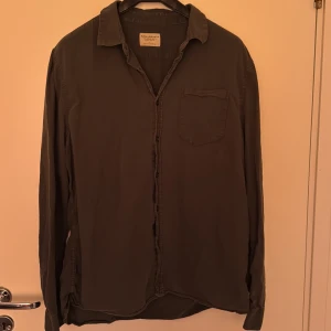 Mörkgrön skjorta från Nudie Jeans - Snygg mörkgrön skjorta från Nudie Jeans i 100% ekologisk bomull. Klassisk modell med krage, bröstficka och knäppning framtill. Perfekt för dig som gillar stilrena och enkla plagg med en avslappnad vibe. KAN GÅ NER I PRIS VID EN SNABB AFFÄR!!