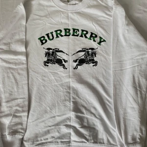 Burberry tröja - Vit långärmad tröja från Burberry. Klassisk rund halsringning och ribbade muddar. Tillverkad i mjuk bomull, perfekt för en clean stil. Storlek S. Priset kan diskuteras 😊
