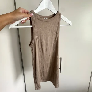 Beige topp - Beige/brun, tight och ärmlös linnetopp med rund halsringning. Perfekt att matcha med jeans eller shorts. Vääärldens mjukaste material som formas efter kroppen. Använd några gånger men har inga defekter💖