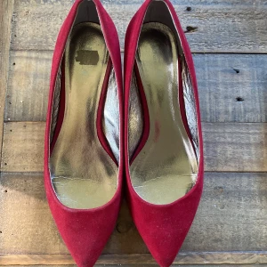 Röda pumps med spetsig tå - Snygga röda pumps i mockaimitation med spetsig tå och låg klack. Insidan är metallicfärgad och skon har en klassisk, elegant siluett. Perfekta för dig som vill sticka ut med färg och stil.