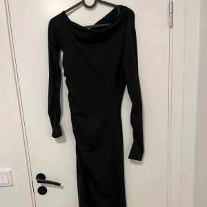 Svart långklänning med asymmetrisk axel - Säljer en svart långklänning med lång ärm och snygg asymmetrisk axel. Klänningen har en elegant, figurnära passform och är tillverkad i ett mjukt, stretchigt material som sitter skönt. Perfekt för dig som gillar stilrena och moderna plagg.