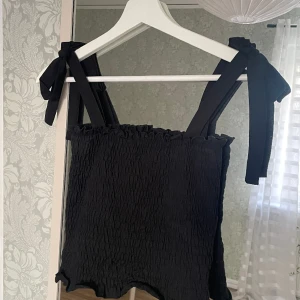 Svart linne - Ett jättefint svart linne med justerbara knytband i axlarna🌺 Inköpt på ginatricot, i storlek s men är i ett stretchigt material så skulle säga att en xs och en m också kan ha den! Kommer inte till användning längre och därför säljer jag den. 