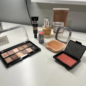 RESERVERAT | Sminkpaket med bas, ögon och kinder - Säljer ett komplett sminkkit med Maybelline The Nudes ögonskuggspalett i bruna och guldiga toner, L'Oréal bronzer, W7 Blush Rebel rouge i rosa, CAIA foundation (3W), IT Cosmetics concealer (oanvänd) , Milk Makeup stick (perk), samt The Ordinary solskydd. Perfekt för en snygg bas och markerade ögon. Alla produkter är korrekt saniterade (endast använd på hand) eller oanvända.