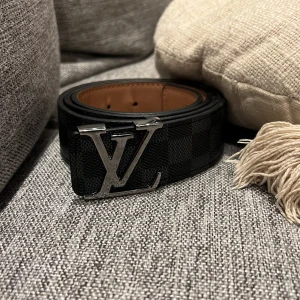 Svart bälte med rutigt mönster - Svart bälte med rutigt mönster och guldigt märke på framsidan, den passar väldigt snyggt till ortenstilen, grisch och även med kostym som kommer vrida huvuden på folk, den är väldigt manlig och mogen för ett bra pris