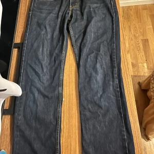 Levi's 501 mörkblå jeans straight fit - Säljer ett par Levi's 501 jeans i mörkblå denim. Byxorna har fem fickor, synliga kontrastsömmar och den ikoniska läderpatchen bak i midjan.