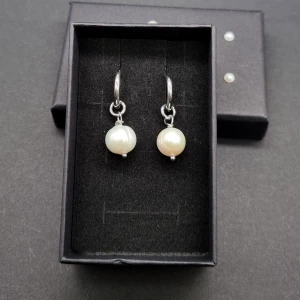 Silvriga örhängen med vita pärlor - Rostfritt stål . Havets pärlor 