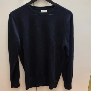 Mörkblå stickad tröja från a days march - En klassisk mörkblå stickad tröja från Sand med rund halsringning och långa ärmar. Perfekt för lager-på-lager och enkel att matcha med jeans eller chinos. Mjuk och skön känsla tack vare det stickade materialet.