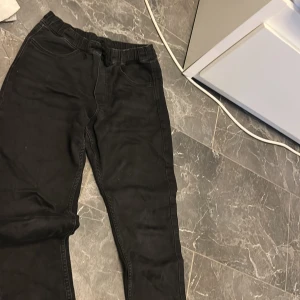 Svarta mjukisbyxor från H&M med snörning - Svarta mjukisbyxor från H&M med elastisk midja och snörning. Byxorna har två framfickor och två bakfickor, tillverkade i supermjuk bomullsmix. Perfekta för en chill och avslappnad stil.