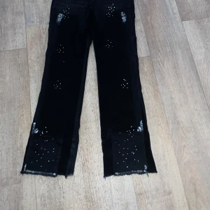 Flates jeans - Unika svarta jeans med råa benslut och vita stänk samt prickar som ger en cool, kreativ vibe. Raka ben och normal passform. Perfekta för dig som vill sticka ut med en edgy streetstil.