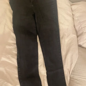 Svarta jeansbyxor från Gina Tricot - Svarta jeansbyxor från Gina Tricot i storlek 34. Modellen har smal passform med klassisk femficksdesign och dragkedja. Jeansen har råa, avklippta benslut för en edgy vibe. Perfekta till sneakers eller boots.