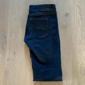 Mörkblå Replay jeans LUZ W29 L32 - Säljer ett par mörkblå jeans från Replay, modell LUZ. Klassisk femficksdesign, snygg tvätt och raka ben. Jeansen är i stretchigt denim och har Replay-logga på bakfickan och i midjan. Perfekta för dig som gillar stilrena och bekväma jeans. Nästan som ny. Fraktar inom 12-24 timmar