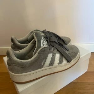 Grå Adidas Campus 00s - Hej! Säljer mina Adidas campus 00s eftersom dom inte kommer till nytta längre!(Har bytt till gråa skosnören) nypris 1000kr mitt pris 300kr🩷