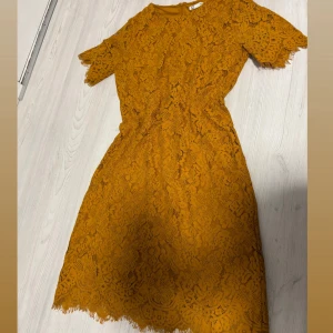 Gul spetsklänning från Cubus - Klänning i spets med blommigt mönster. Perfekt för dig som vill sticka ut med en färgstark look. Dragkedja i ryggen för enkel påklädning.