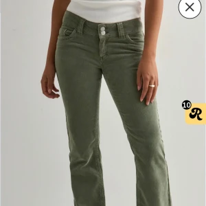 Gröna manchesterbyxor med bootcut - Snygga gröna manchesterbyxor med bootcut och låg midja. Byxorna har två knappar i midjan, klassiska fickor fram och bak samt coola detaljer på bakfickorna. Perfekta för dig som vill ha en trendig och bekväm look.
