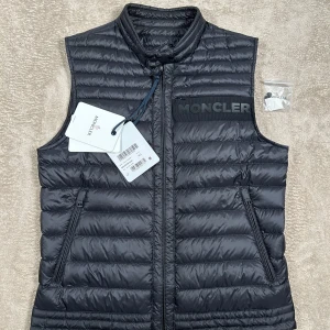 Moncler Roussillon Vest - Riktigt snygg och stilren väst av Moncler med en unik design! 10/10 skick nästintill ny. Lapp och extra knappar följer med! St M