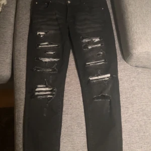 Amiri jeans - Svarta jeans från Amiri med rejält slitna och trasiga detaljer framtill. Skinny fit med klassisk femficksdesign och dragkedjegylf. Jeansen är tillverkade i stretchig denim för en tajt och bekväm passform. Perfekt för dig som gillar en edgy streetstil.