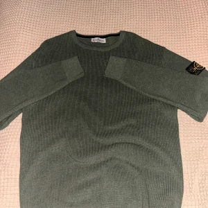 Grön Stone Island tröja L  - Säljer en grön långärmad tröja från Stone Island i storlek XXL men sitter som L. Tröjan är ribbstickad och har den klassiska Stone Island-loggan på ärmen. Tillverkad i 100% bomull, perfekt för dig som gillar stilrena och bekväma plagg. Aldrig använd, hör av er om ni har några frågor🫡