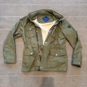 Olivgrön feildjacket från GANT - Snygg olivgrön feildjacket från GANT. Nypris cirka 3000 (går ej o köpa längre). Kan minskas i midjan med hjälp av dragsko. 