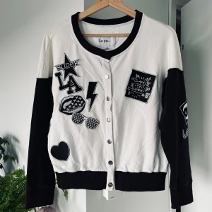Svartvit kofta med patches från La par - Svartvit collegejacka med tryck och broderier, Gott Skick! Välvårdad och sparsamt använd. Material: 95.3 % bomull Storlek: 165/88A (M) Finns för upphämtning i Kista, Stockholm eller leverans enligt överenskommelse.