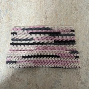 Hand virkad randig kattör mössa - Handvirkad kattör mössa med bred passform i mjuka nyanser av rosa, grått, brunt och beige. Snyggt randigt mönster med oregelbundna ränder som ger en unik look. Perfekt för ungdomar som vill sticka ut med en personlig accessoar.