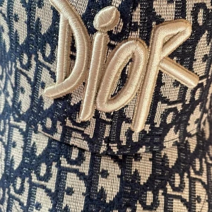 Dior keps i blått monogram - Snygg keps från Dior med ikoniskt blått och vitt monogrammönster. Stor broderad Dior-logga framtill i beige. Justerbar rem baktill med metallspänne där Dior är ingraverat. Kepsen är tillverkad i ett vävt material som känns lyxigt och trendigt.