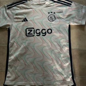 Ajax tredjekit tshirt  - Ajax tröja från adidas. En fin luftig tröja med  lite rosa och gröna detaljer. Nästan aldrig använd. Är i storlek L men funkar även som M. Nypris 400-600