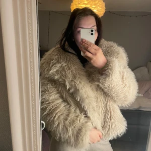 Beige fluffig pälsjacka - Säljer en superfluffig och oversized beige pälsjacka med bred krage. Jackan har lång ärm och är perfekt för dig som vill sticka ut med en mysig och trendig look. Passar perfekt till kalla dagar och ger en cool vibe. Nypris 500