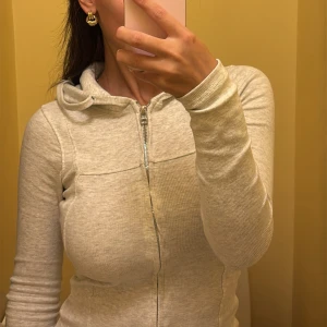 Ljusgrå hoodie med utsvängda byxor  - Ljusgrå hoodie med hel dragkedja framtill och huva tillsammans med matchande mjukis byxor från bohoo. 