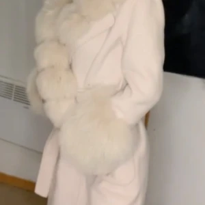 KASHMERIPANSA// Offwhite - Otroligt vacker och exklusiv kappa med två sidfickor och en fyllig, vacker pälskrage.  Denna vackra pälsjacka har många fina detaljer, och kan bäras med ett par sneakers för en avslappnad look eller höga stövlar för en mer elegant look. 6900 DDK