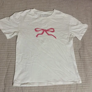 Vit t-shirt med rosa rosett - Har aldrig blivit använd så bra skick