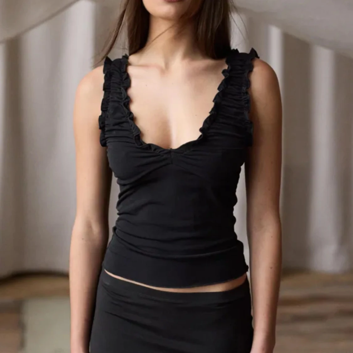 Svart volangtop med djup v-ringning