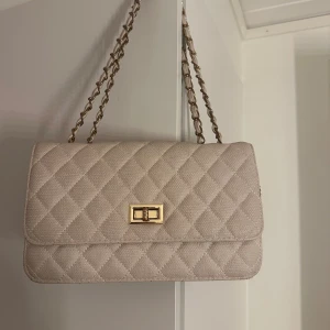 Beige axelväska  - Stilren beige axelväska med fint mönster. Väskan är i från New Yorker och har normalt slitage (se bilder). 