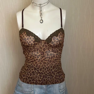 Leopardmönstrad linnetopp från Zara - Säljer en leopardmönstrad linnetopp från Zara med tunna bruna axelband och olivgröna spetsdetaljer vid bysten. Toppen är figurnära och har en transparent känsla, perfekt för att skapa en cool och trendig look.