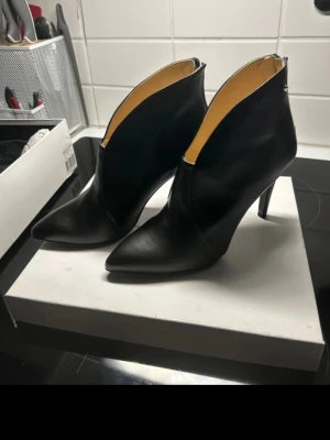 Svarta stövletter i skinn från Sofie Bly - Säljer ett par svarta stövletter från Sofie Bly i slätt skinn. Skorna har spetsig tå, hög klack och dragkedja bak. Snygg, stilren design som passar till många looks. Kommer med originalpåse.