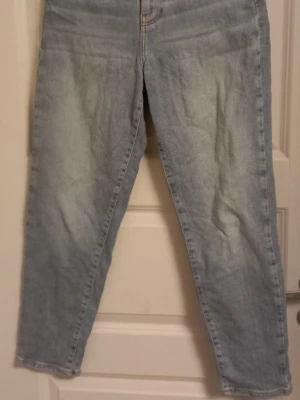 Ljusblå raka jeans  - Säljer ett par ljusblå jeans med klassisk femficksdesign och raka ben storlek 34. Jeansen har en enkel look med kontrastsömmar och är tillverkade i ett slitstarkt bomullsjeanstyg. Perfekta till sneakers eller boots för en chill vardagsstil.